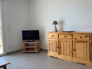 uma sala de estar com televisão e uma cómoda de madeira em Appartement Narbonne, 3 pièces, 6 personnes - FR-1-229B-23 em Narbona