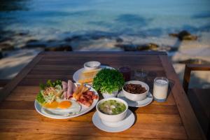 a table with plates of breakfast food on the beach at Siam Beach Resort Koh Kood in Ko Kood