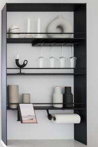 a black shelf with glasses and vases on it at Suite Portus - Design apartment by the sea in Hanko
