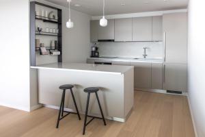 una cucina con armadi bianchi e 2 sgabelli a un bancone di Suite Portus - Design apartment by the sea a Hanko