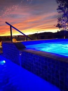 - une piscine avec éclairage bleu en face d'un coucher de soleil dans l'établissement Finca Cazosa, à Valle de Guadalupe