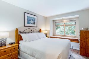 um quarto com uma cama branca e uma janela em Lake Placid Coach House 17 em Whistler