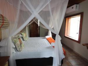a bedroom with a canopy bed with white curtains at Adventure Bush House II in Marloth Park