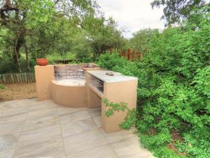 a backyard patio with a sink and some bushes at Adventure Bush House II in Marloth Park