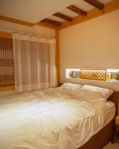 a bedroom with a large white bed with a window at Stay Gyeongju in Gyeongju