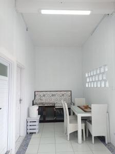 Habitación blanca con mesa y sillas en Mommy Cafe Guesthouse en Pangandaran