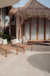 a resort with two benches and a straw umbrella at Belajar Bali Boutique Hotel and Retreat in Canggu