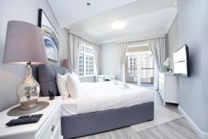 ein Schlafzimmer mit einem weißen Bett und einem Schreibtisch mit einer Lampe in der Unterkunft Lux Living on Palm Jumeirah With Beach Access & Complimentary Golf in Dubai