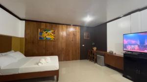 a bedroom with a bed and a flat screen tv at Ohana Hometel in Sorsogon