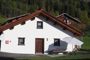 a white house with a table and an umbrella at Alte Sennerei in Ober-Says