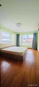 Cama grande en habitación con suelo de madera en Top floor sunny bedroom near Fudan, en Shanghái