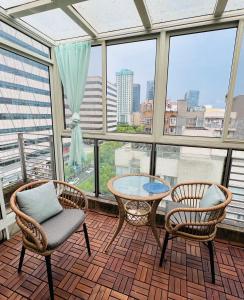 balcón con 2 sillas, mesa y algunas ventanas en Top floor sunny bedroom near Fudan, en Shanghái