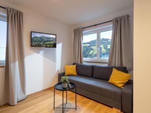 sala de estar con sofá gris y almohadas amarillas en Bergzeit Appartement, en Hopfgarten im Brixental