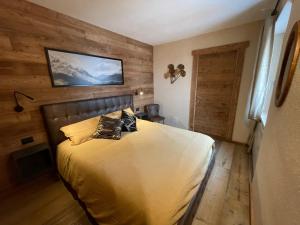 1 dormitorio con 1 cama con pared de madera en Apartment Gran Baita Sauze d'Oulx, en Sauze dʼOulx