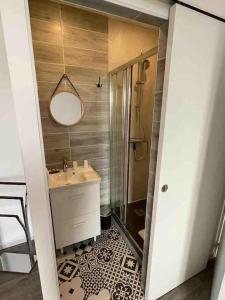 een badkamer met een wastafel, een douche en een spiegel bij Grain de café Barneville Plage in Barneville-Carteret