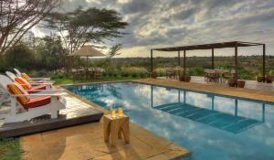 a swimming pool with lounge chairs and a table at Ololo Safari Lodge & Farm in Nairobi
