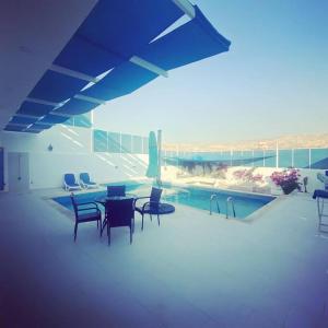 a patio with a table and chairs next to a pool at Aqua Blue Villa-Dead Sea, Jordan in Amman