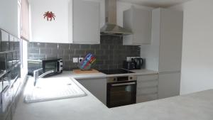 uma cozinha com armários brancos, um lavatório e um fogão em The Getaway - Modern 2 Bedroom Brixham Bungalow with sea peeps em Brixham