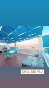 Aqua Blue Villa-Dead Sea, Jordan في عمّان: فناء به مظلة زرقاء على طاولة وكراسي