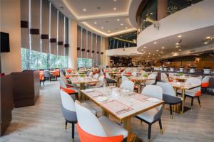 a restaurant with wooden tables and white chairs at Grand Paragon Hotel Johor Bahru in Johor Bahru