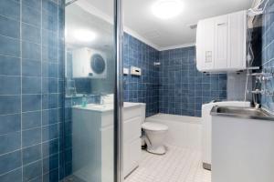 Un baño con azulejos azules, inodoro y lavabo. en Central Getaway With Ocean Views - CoastHM, en Gold Coast
