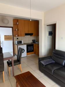 a living room with a black couch and a kitchen at Green Nondas Hill A in Larnaka
