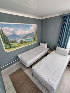 two beds in a room with a painting on the wall at 4 Seasons in Karakol