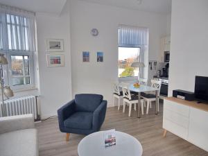 a living room with a blue chair and a table at Haus Therese *FeWo 9* in Wittdün