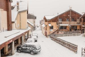 śnieżna ulica w mieście z zaparkowanymi samochodami w obiekcie Chalet M, pied des pistes et garage w mieście Montgenèvre
