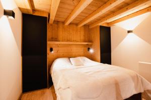 sypialnia z łóżkiem w pokoju z drewnianym sufitem w obiekcie Chalet M, pied des pistes et garage w mieście Montgenèvre