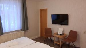 um quarto de hotel com uma cama e uma televisão na parede em Garni-Pension Andrä em Schierke