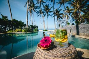 a drink on top of a table next to a pool at Tabanan Villas in Tabanan