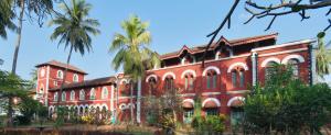 a red brick building with palm trees in front of it at Sawantwadi Palace Boutique Art Hotel in Sawantwadi