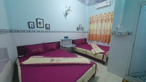 Homestay Nam Du Xanh في Nam Du: سريرين في غرفة ذات أغطية أرجوانية