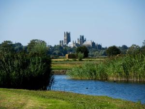 a river in a field with a city in the background at The Old Hall Ely in Ely