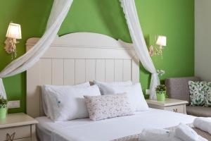 a bedroom with a white bed with green walls at Villa Anthelion in Limenaria