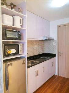 Una pequeña cocina con nevera y microondas. en Cozy studio unit at Sun Residences, en Manila