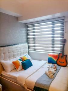 um quarto com uma cama grande e uma guitarra em Cozy studio unit at Sun Residences em Manila