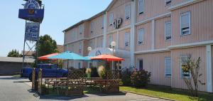 un bâtiment avec des tables et des parasols devant lui dans l'établissement Quick Palace Anglet, à Anglet