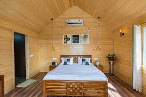 1 dormitorio con 1 cama grande en una habitación de madera en SaffronStays Cottage Glade, Dehradun - luxury wooden cottage, en Dehradun