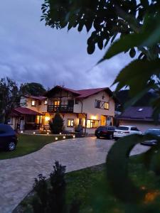 a house with cars parked in front of a driveway at Casa cu Flori in Buşteni