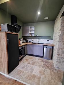 a kitchen with purple cabinets and a black refrigerator at L'appart de Léo et Soso in Bayeux