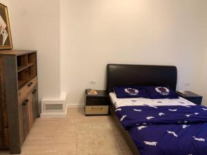 a bedroom with a bed with purple sheets and a dresser at DUO Residence in Dumbrăviţa