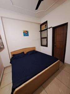 a bedroom with a bed with blue sheets and a door at Private room with Sky Garden in Green Bacchus by Walias in Gurgaon