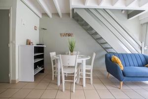 a dining room with a blue couch and a table and chairs at Cottage Opale in Stella-Plage