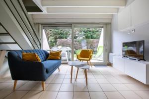 a living room with a blue couch and a yellow chair at Cottage Opale in Stella-Plage