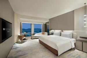 a bedroom with a large white bed and a television at Pullman Shenzhen North in Shenzhen