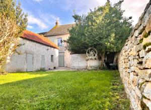 una casa antigua con una pared de piedra y un patio en * La Petite Ferme de Moiry * Maison Indépendante proche du circuit de Magny Cours en Saint-Parize-le-Châtel