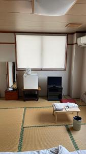 a room with two large windows and a table at はらビジネス旅館 in Wakayama
