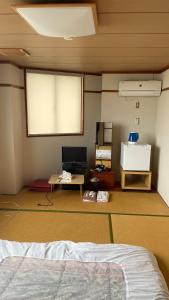 Habitación con cama, mesa y pantalla. en はらビジネス旅館 en Wakayama